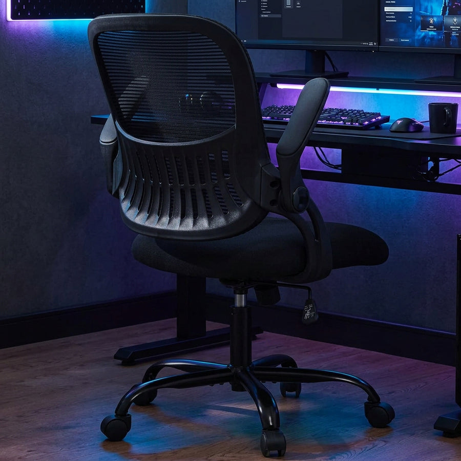 Black office chair in a home office and gaming setting with a desk, dual monitors, a keyboard, and RGB lighting.